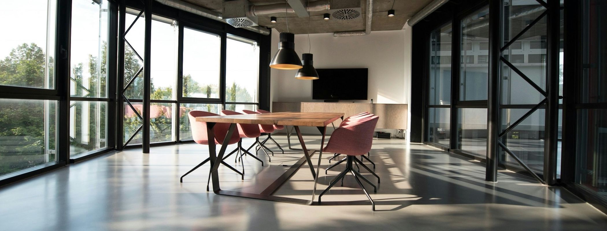 Lichte vergaderruimte met een houten tafel en grote ramen